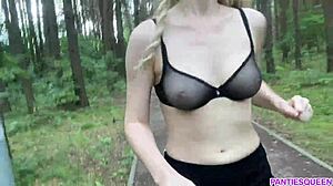 La mujer rubia hace ejercicio al aire libre en el parque, exponiendo su cuerpo desnudo y sus pechos rebotando